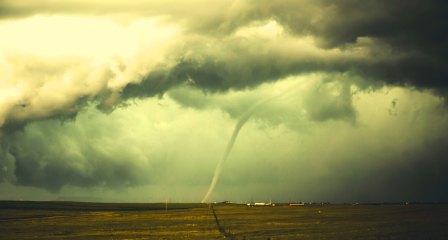 Tornado touching land from storm clouds above