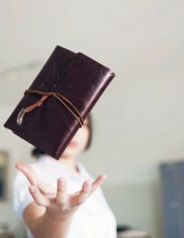 Woman tossing into the air a leather diary and Smartphone