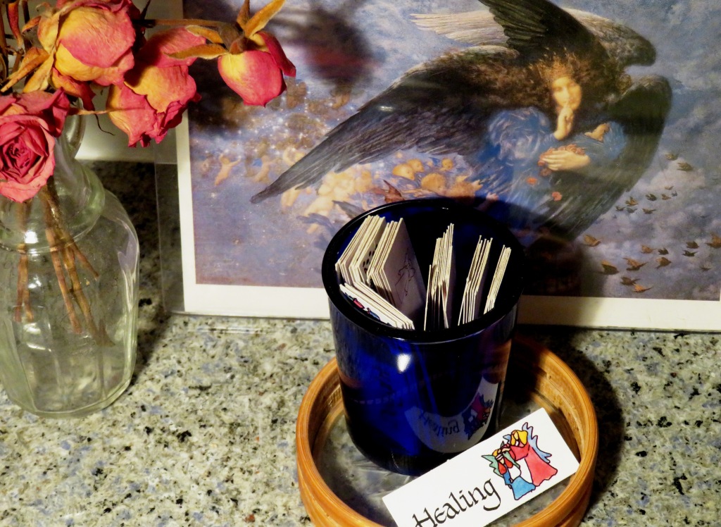 Angel card for Healing amidst container of cards, dried roses and angel card